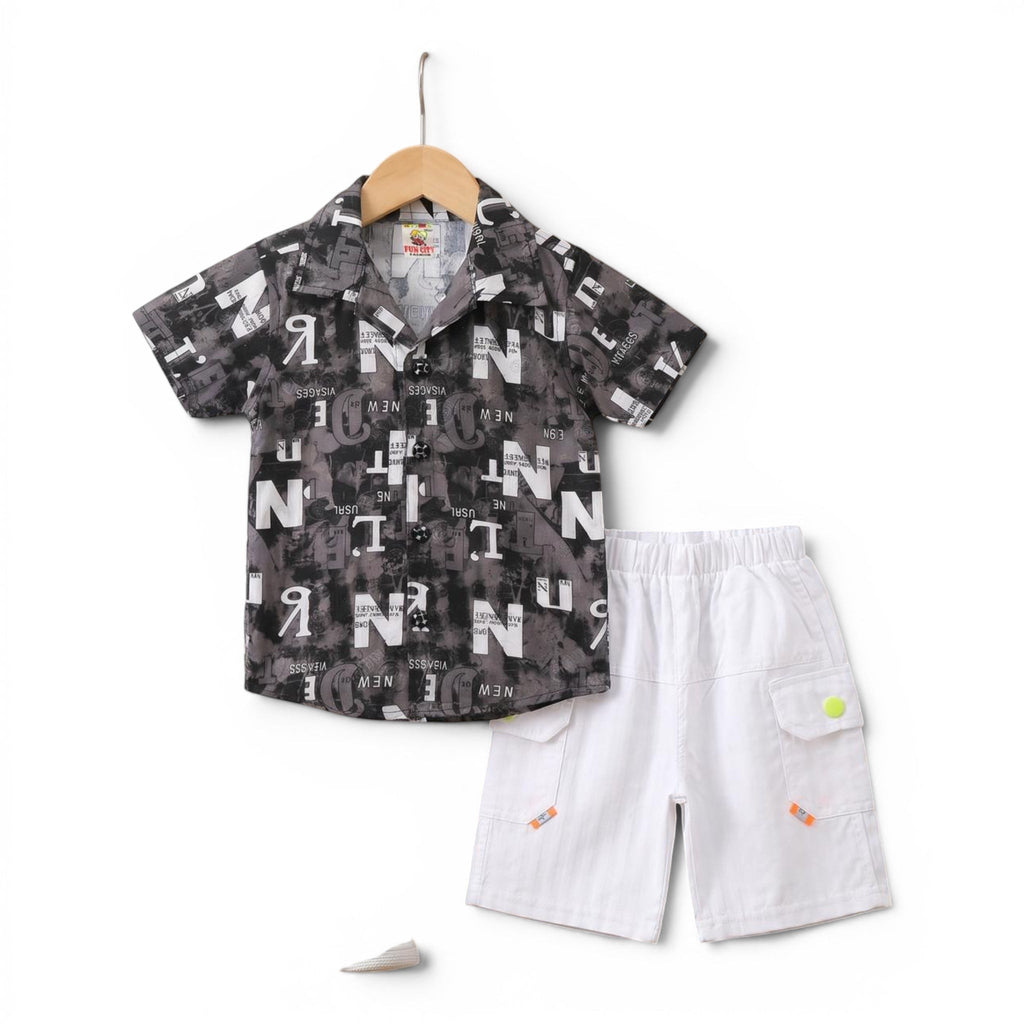 Mini & Mama Boys graphic print short sleeve shirt and white cargo shorts set. Shirt features all-over grey and black text print. Shorts have elastic waist.