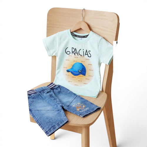 Mini & Mama light mint green graphic t-shirt with "6 GRACIAS" and blue baseball cap, paired with blue denim shorts with graphic detail.