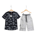 Mini & Mama Boys black graphic t-shirt and white cargo shorts set. T-shirt has all-over letter print. Shorts have drawstring waist and multiple pockets.