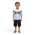 Mini & Mama boys white cotton t-shirt with black graphic print and black cargo shorts. Features smiley face detail.