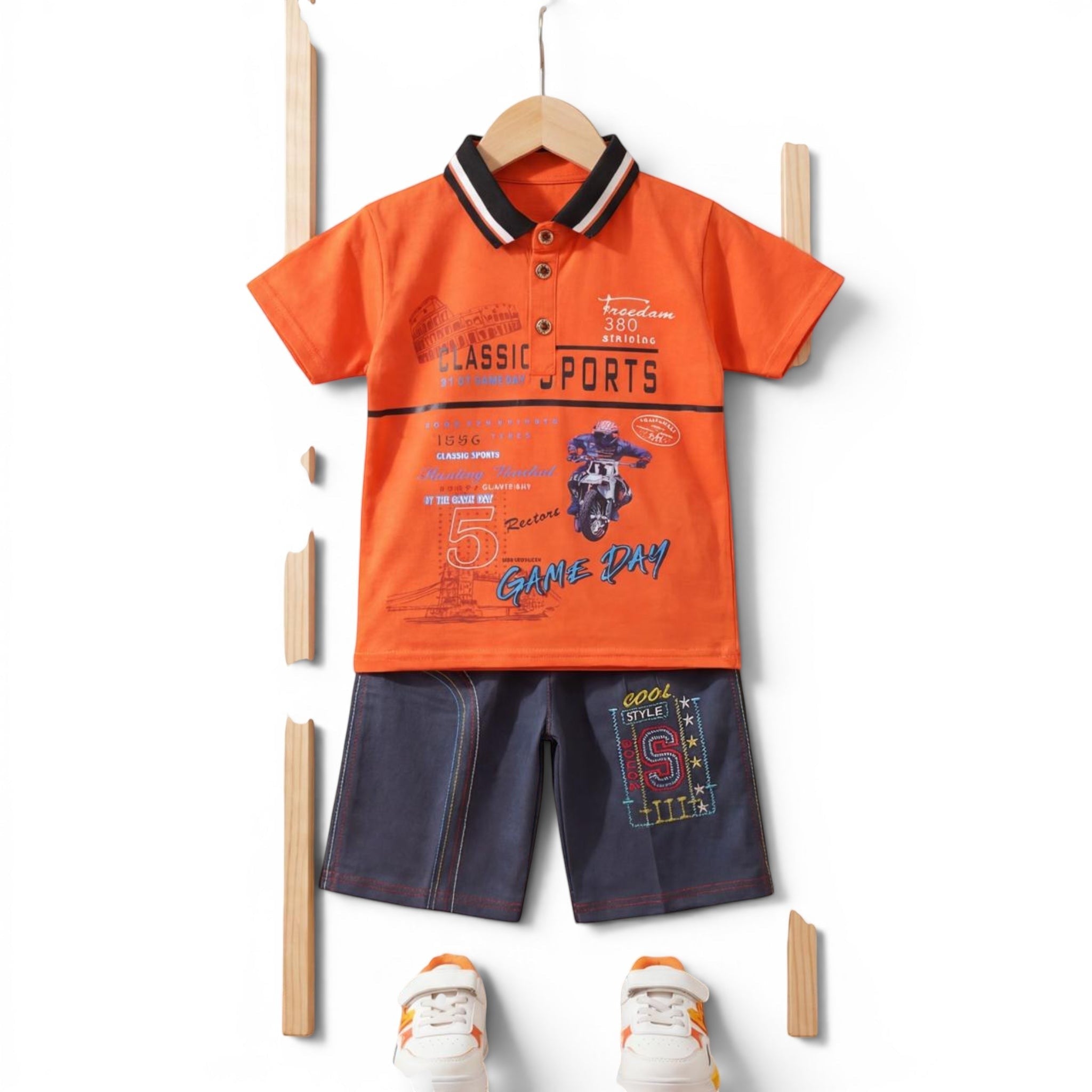 Mini & Mama Boys orange graphic print polo shirt with black and white striped collar and dark wash denim shorts with embroidered S.