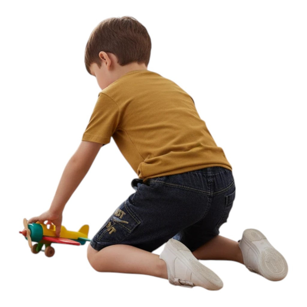 Mini & Mama boys mustard yellow t-shirt and indigo denim shorts set with "Just Do It" graphic. Boy playing with toy airplane.